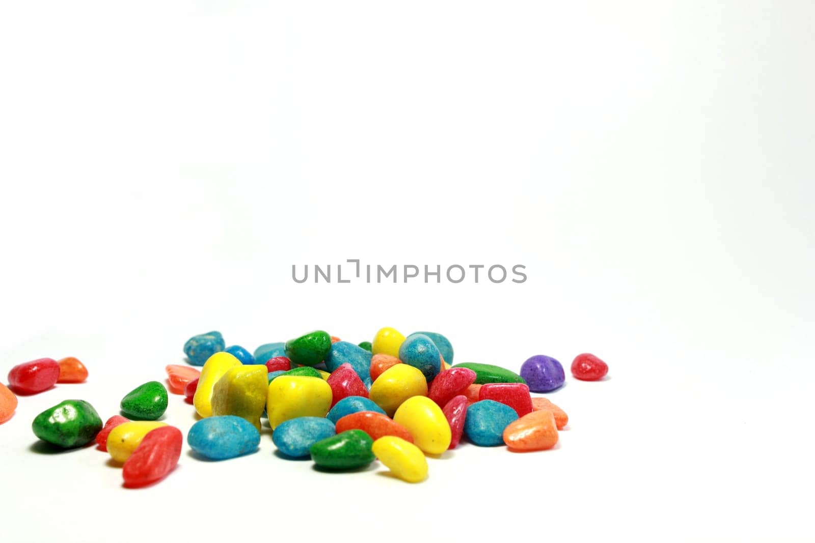 A number of brilliantly coloured pebbles against a white background .