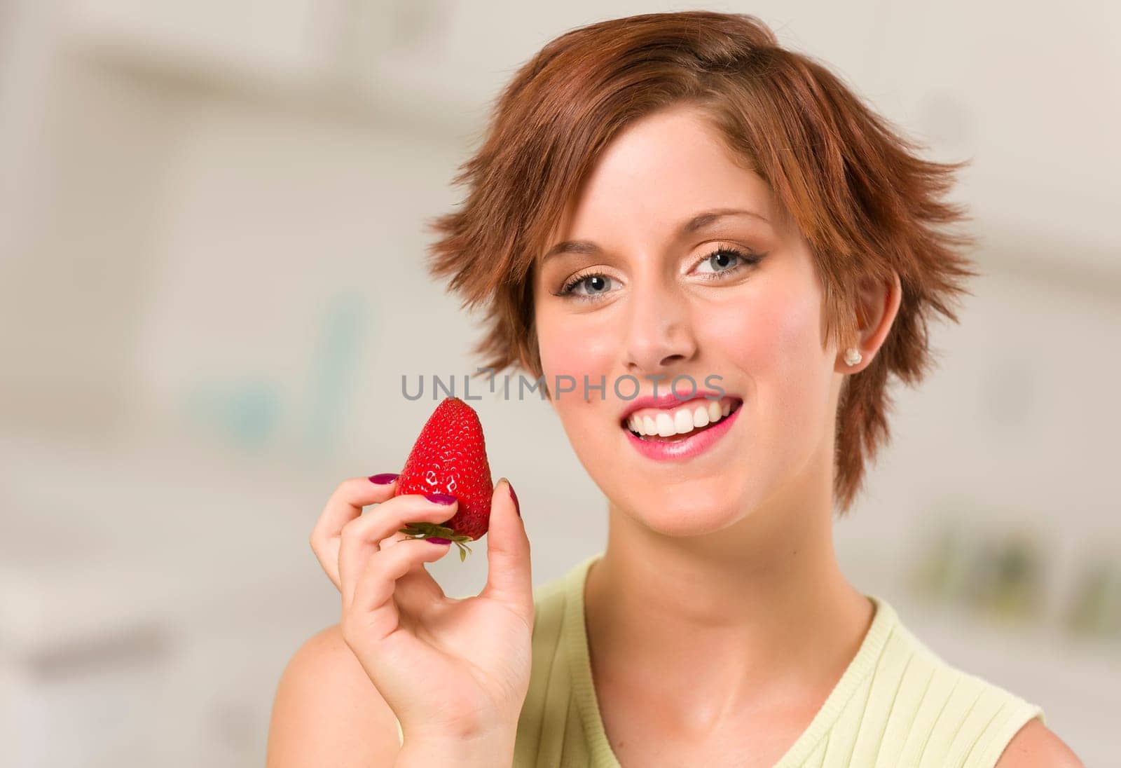 Pretty Red Haired Woman Holding Strawberry in Her Kitchen.