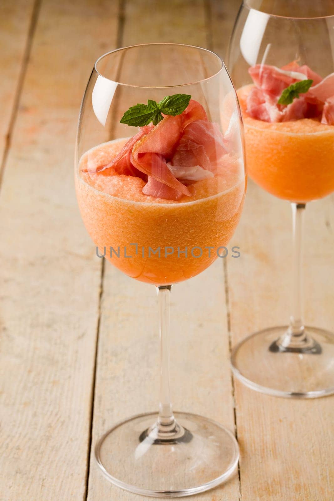 photo of delicious ham and melon cocktail appetizer on wooden table
