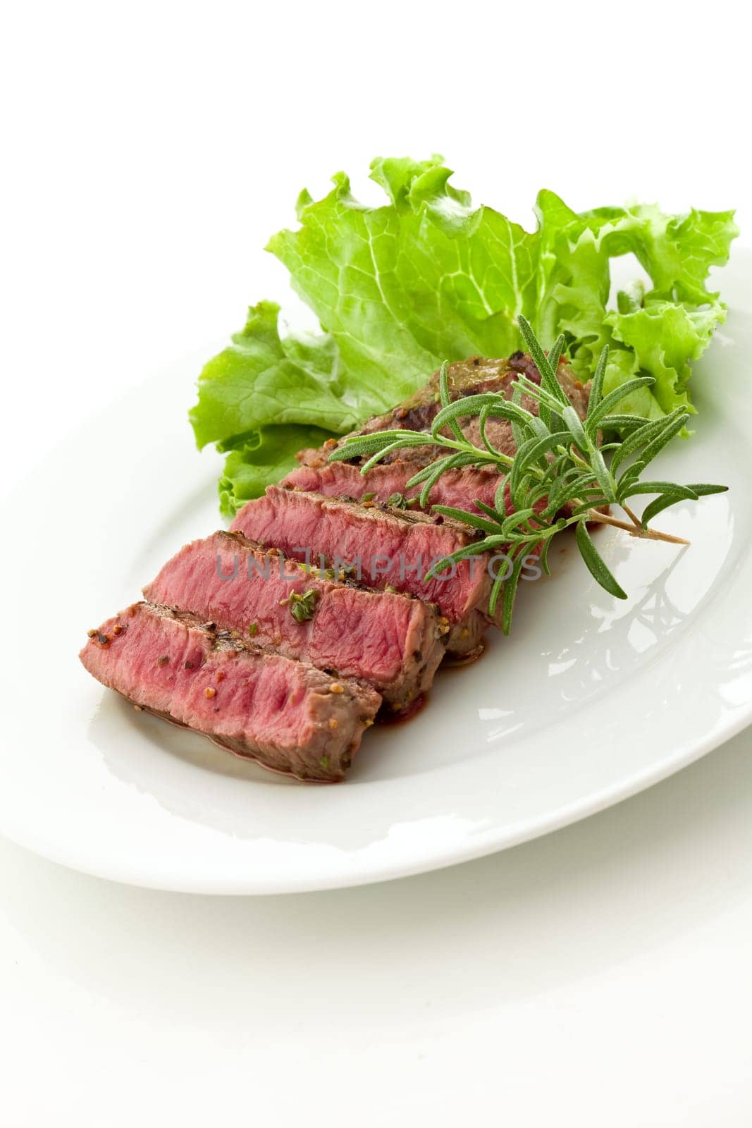 photo of delicious and pefect cooked beaf steak with rosemary and lettuce