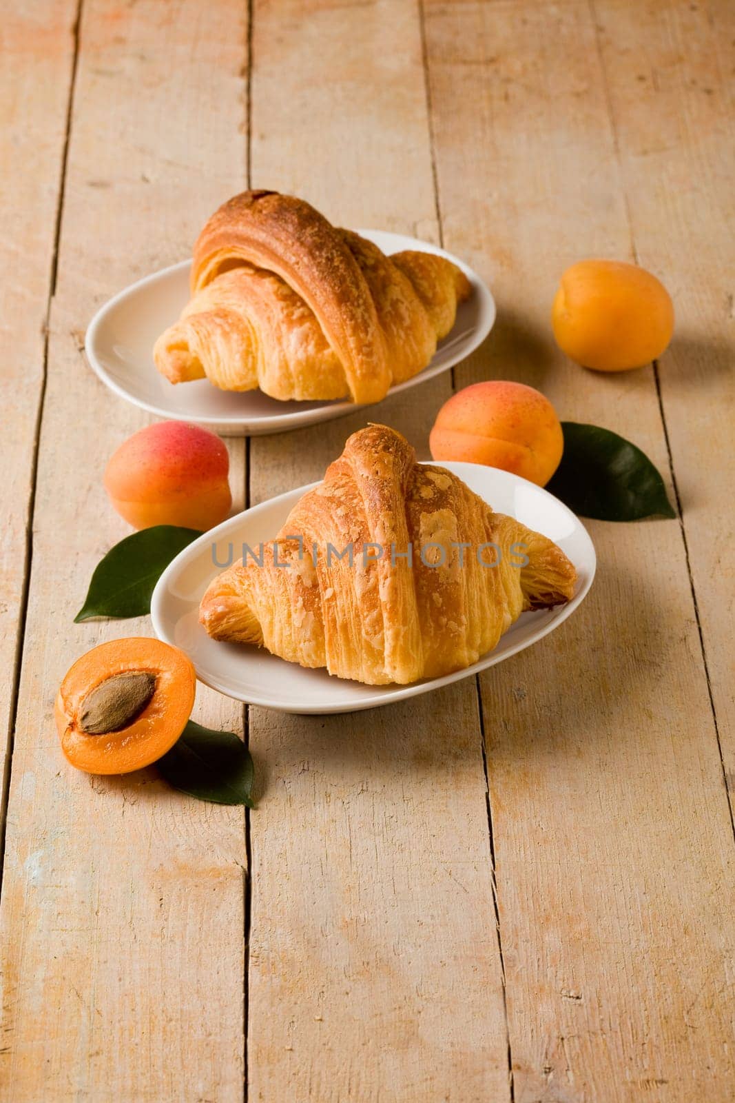 photo of delicious golden croissants with apricot marmalade on wooden table