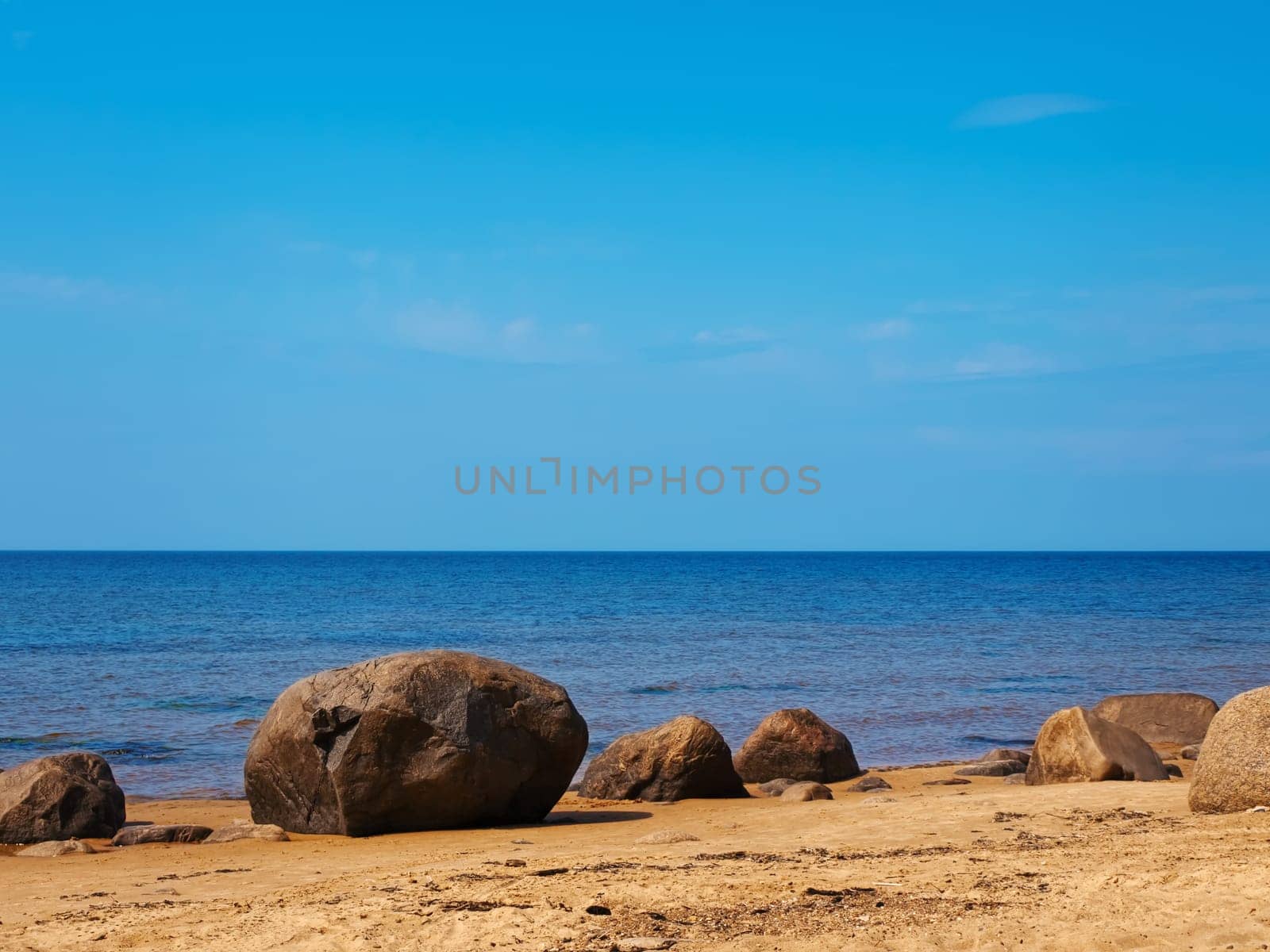 Sea rocky beach in sunny day, blue cloudy sky