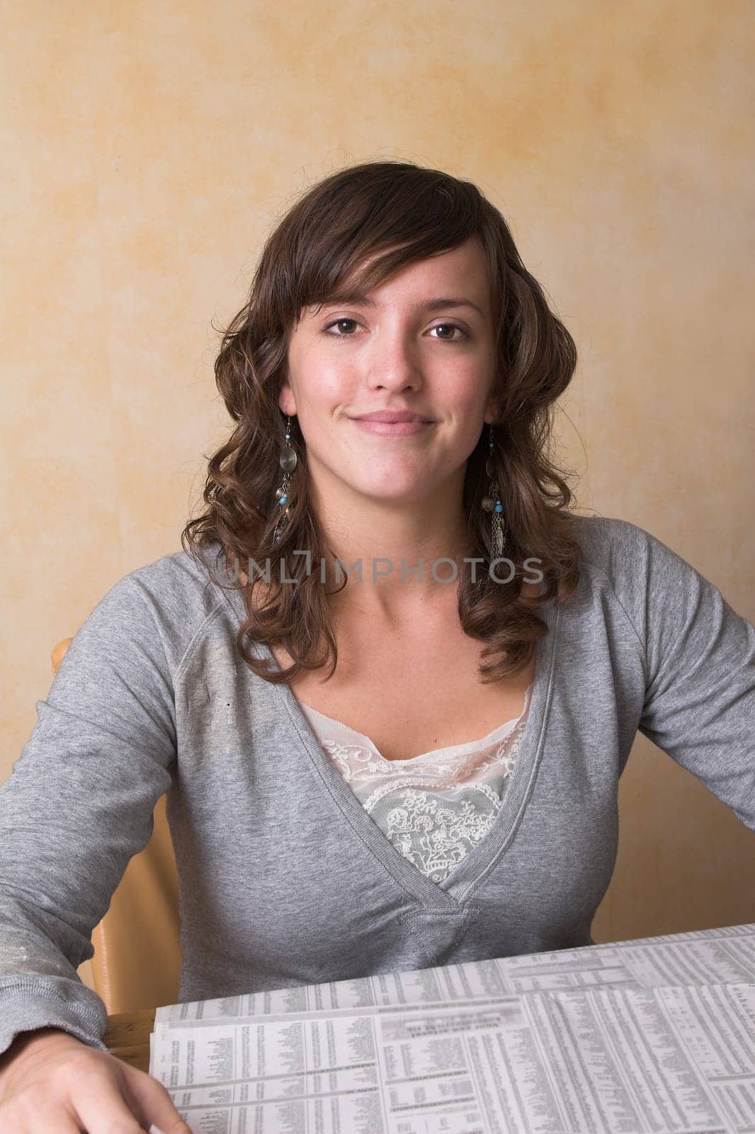 Pretty brunette reading the morning newspaper at the kitchen table