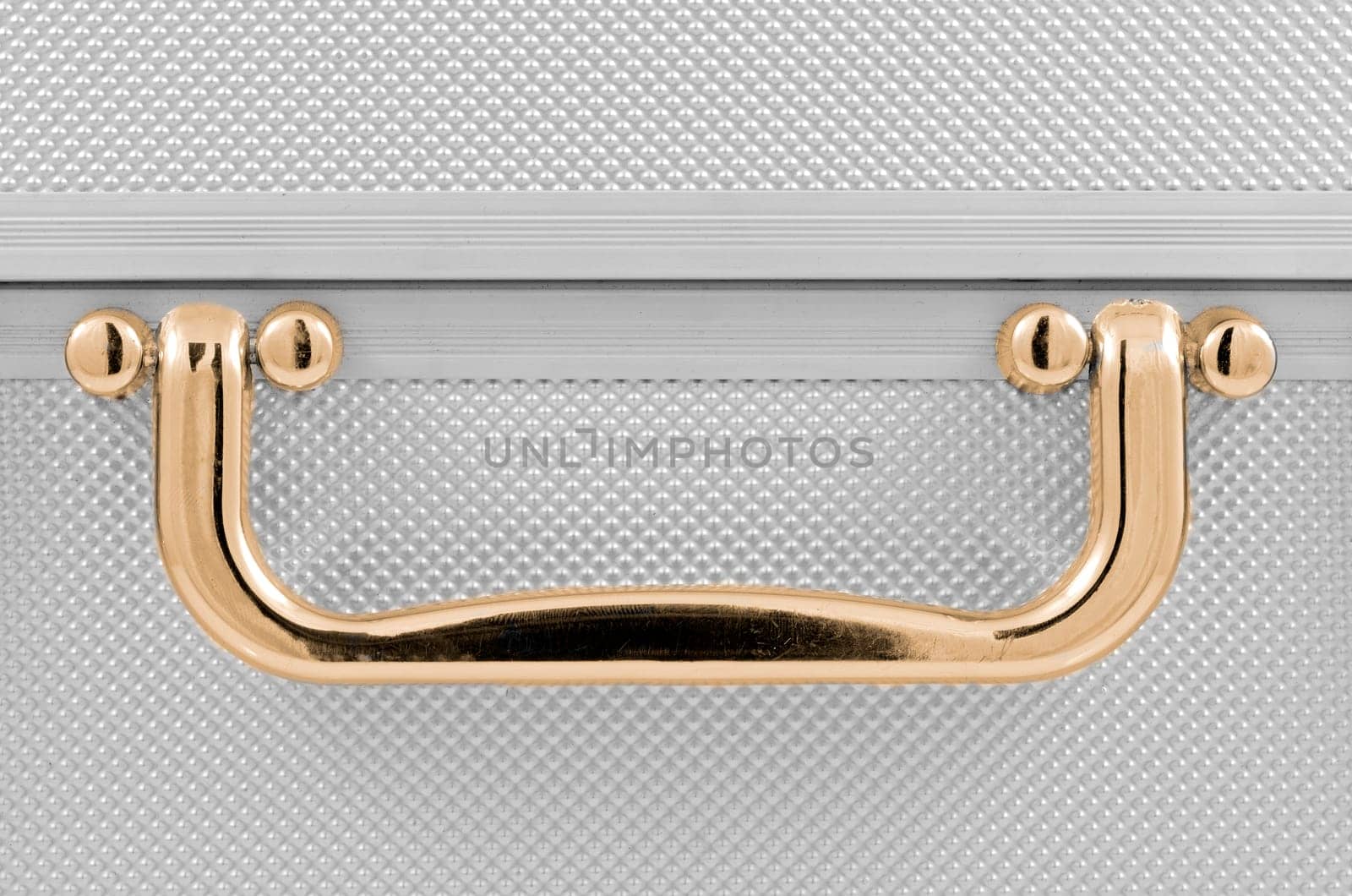 Golden handle detail of an aluminum case.