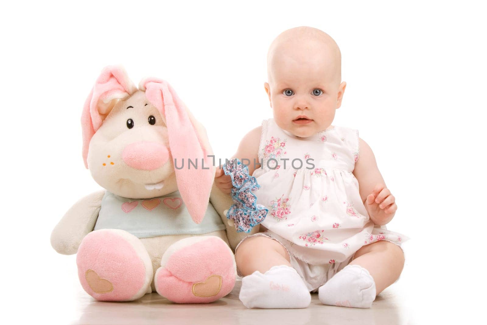 Pretty baby sitting next to giant toy, isolated on white