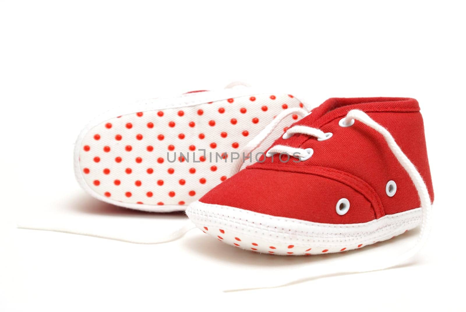 An isolated pair of red baby shoes for the newborn to wear.