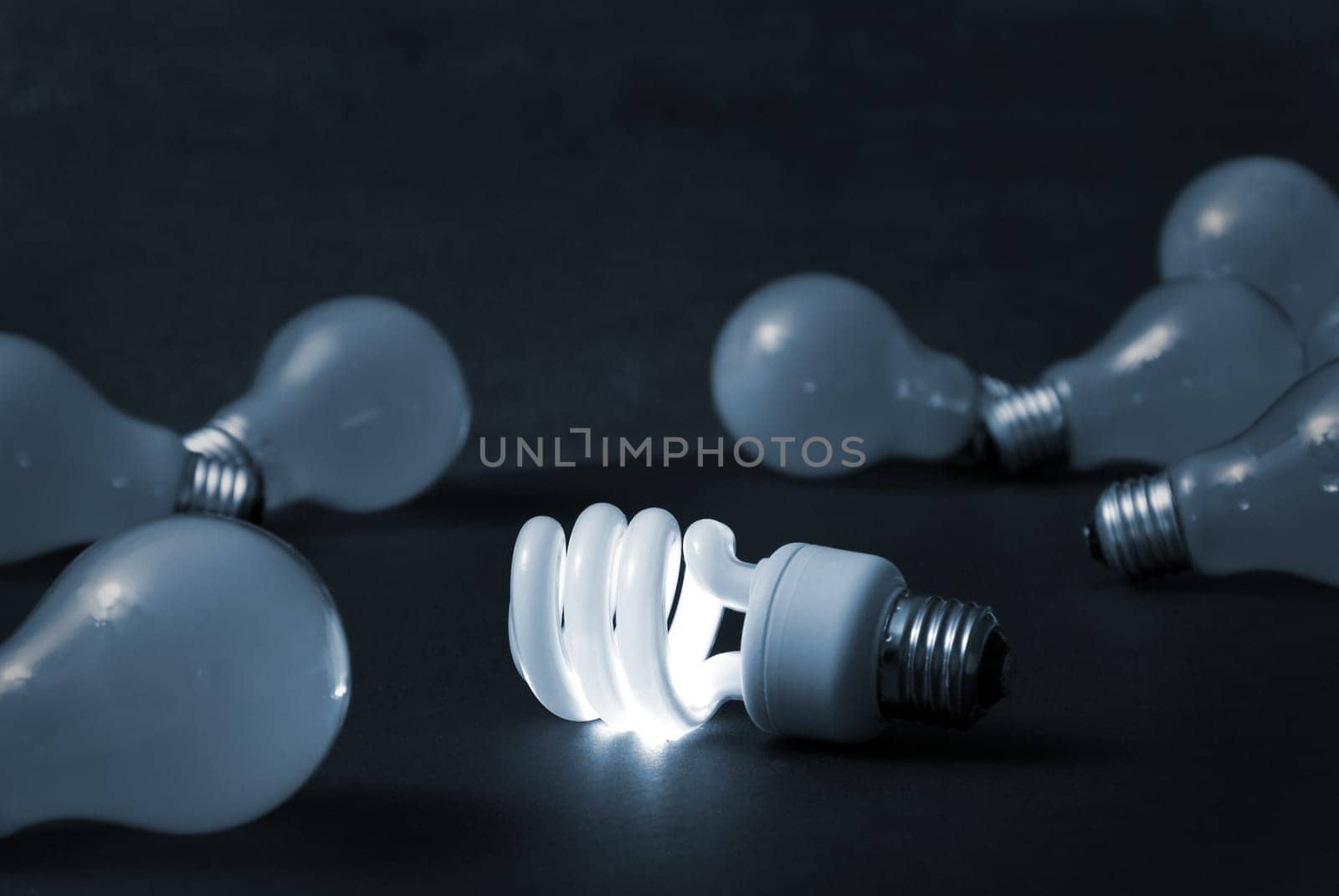 A new energy efficient CFL light bulb shines while the old ones fade into darkness.