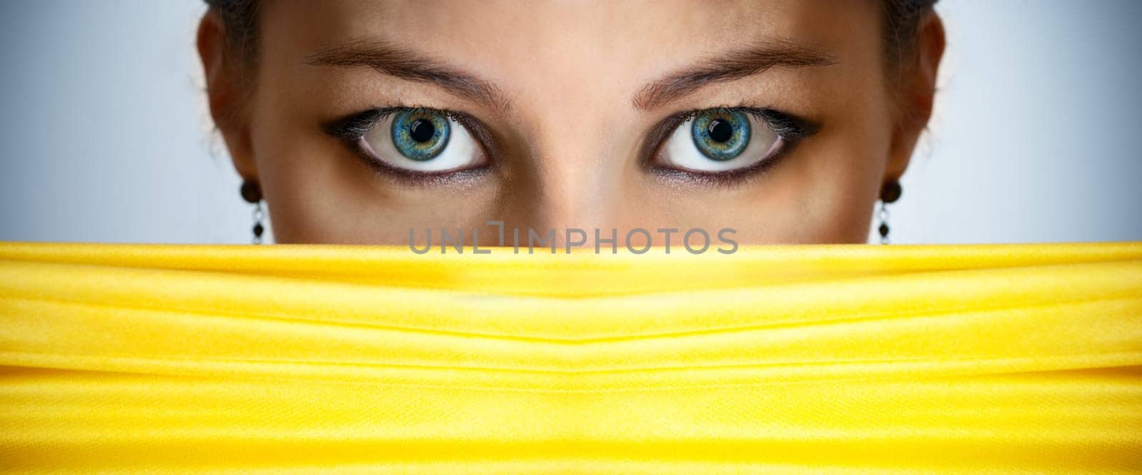 Closeup of beautiful female eyes behind the yellow silk