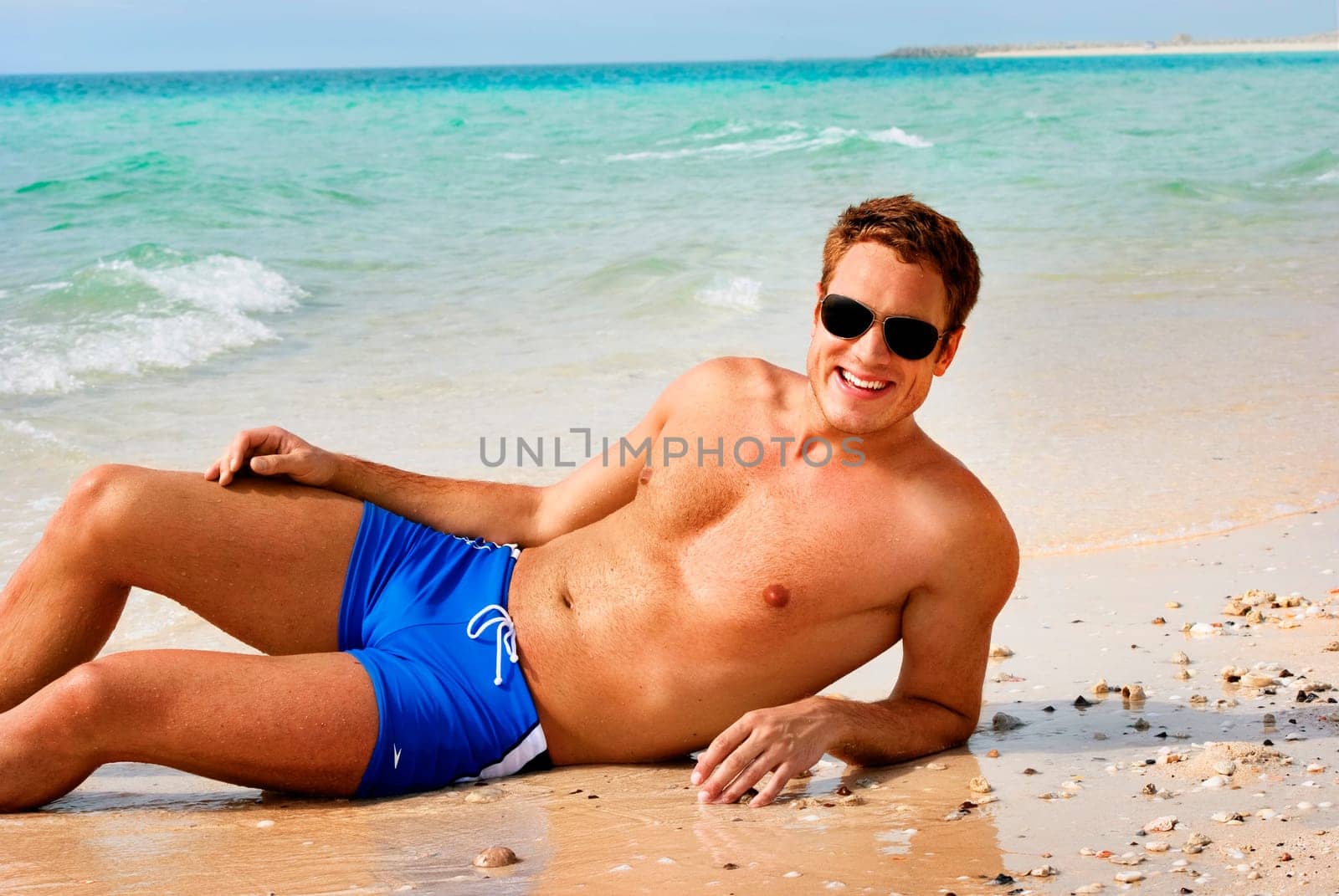 Happy smiling man laying on the beach
