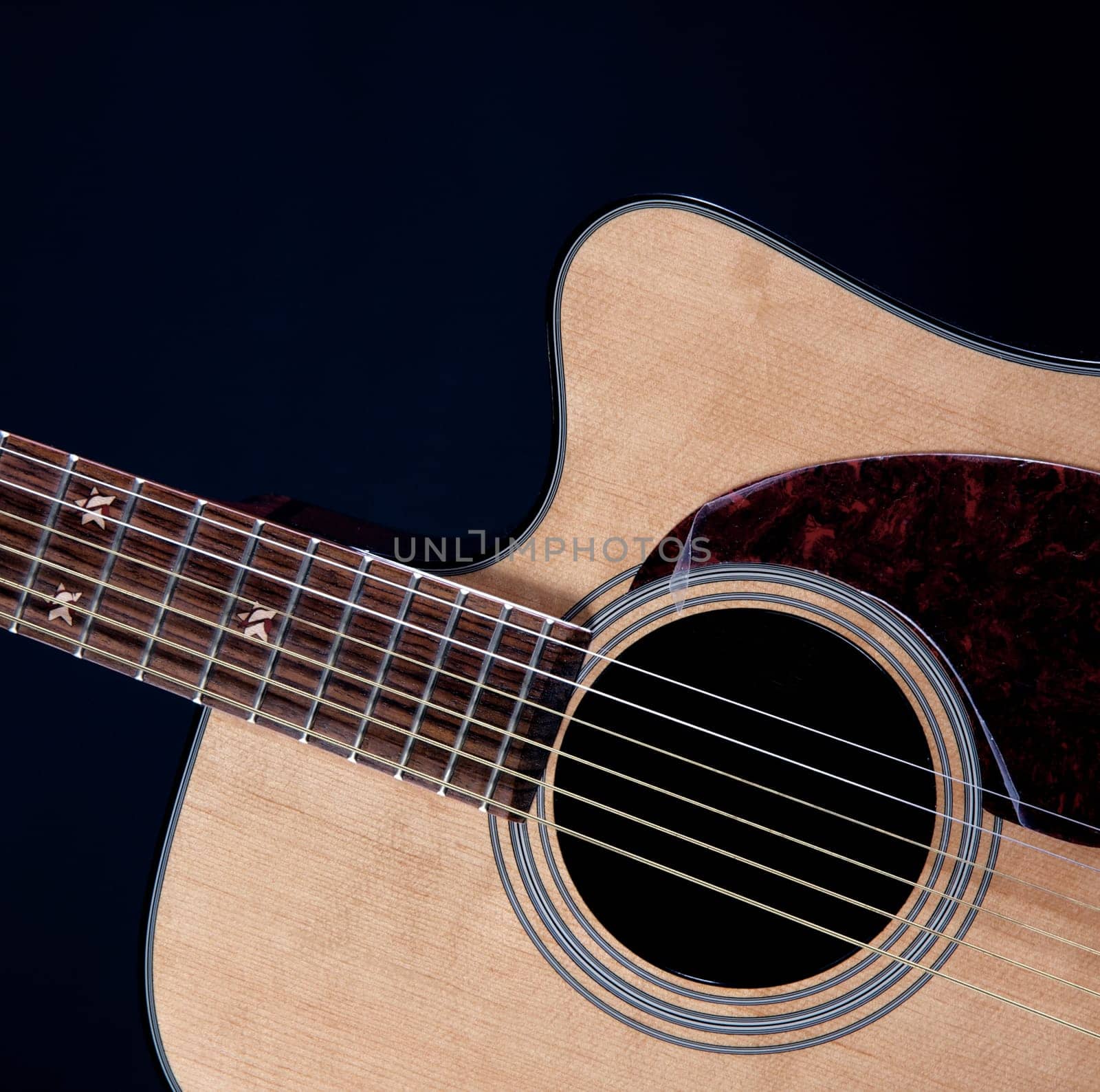 An acoustic guitar isolated against a black background in the square format.
