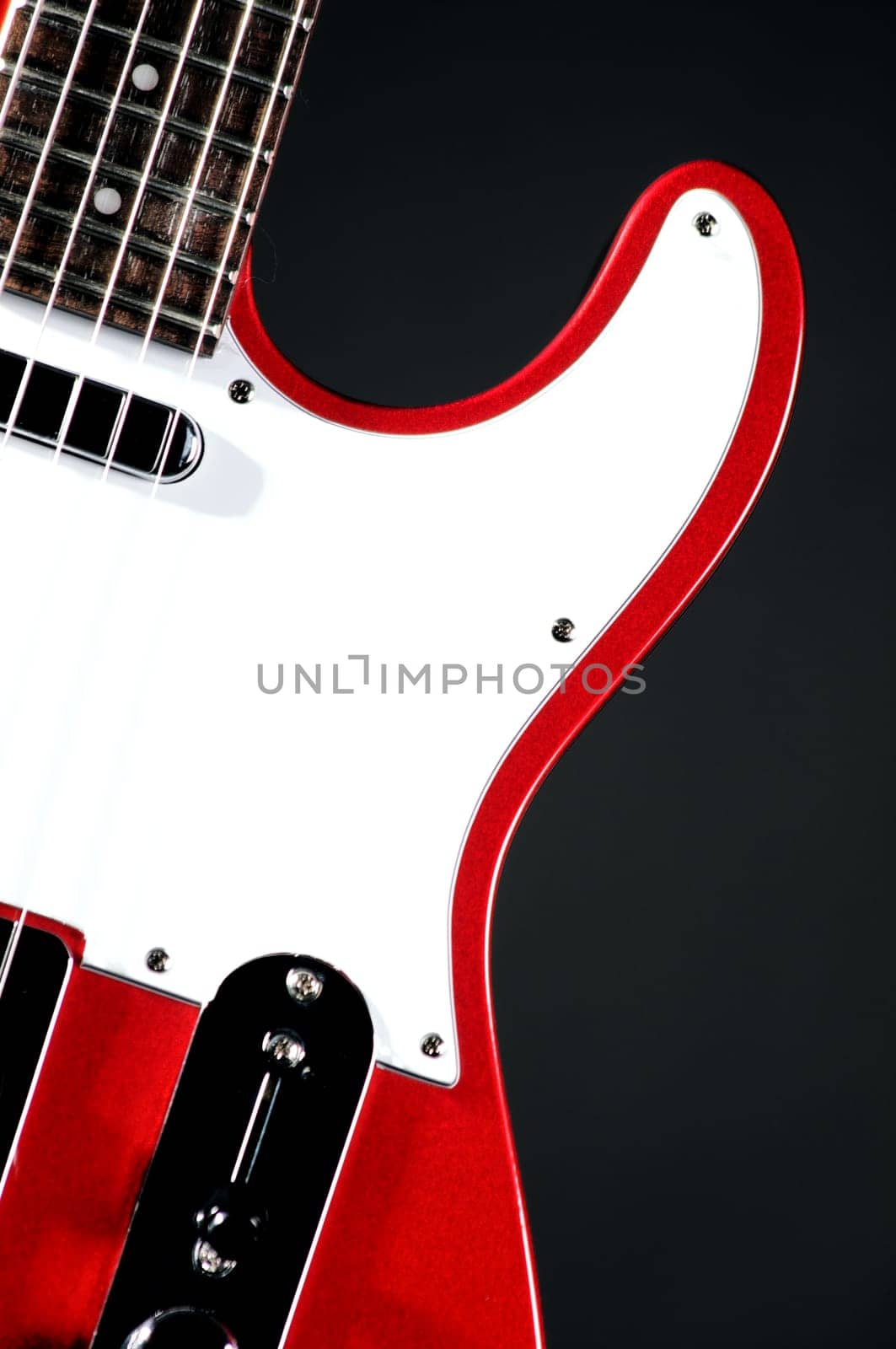 An electric metallic red guitar isolated on a black background in the  vertical format with copy space.