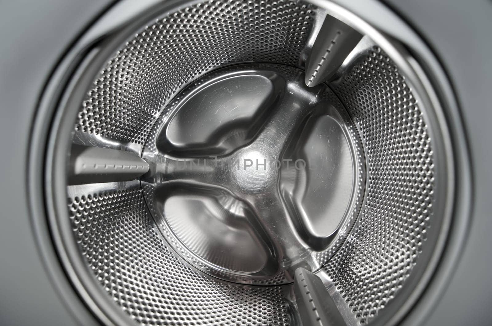 Inside washing machine with detailed view at the metallic drum part.