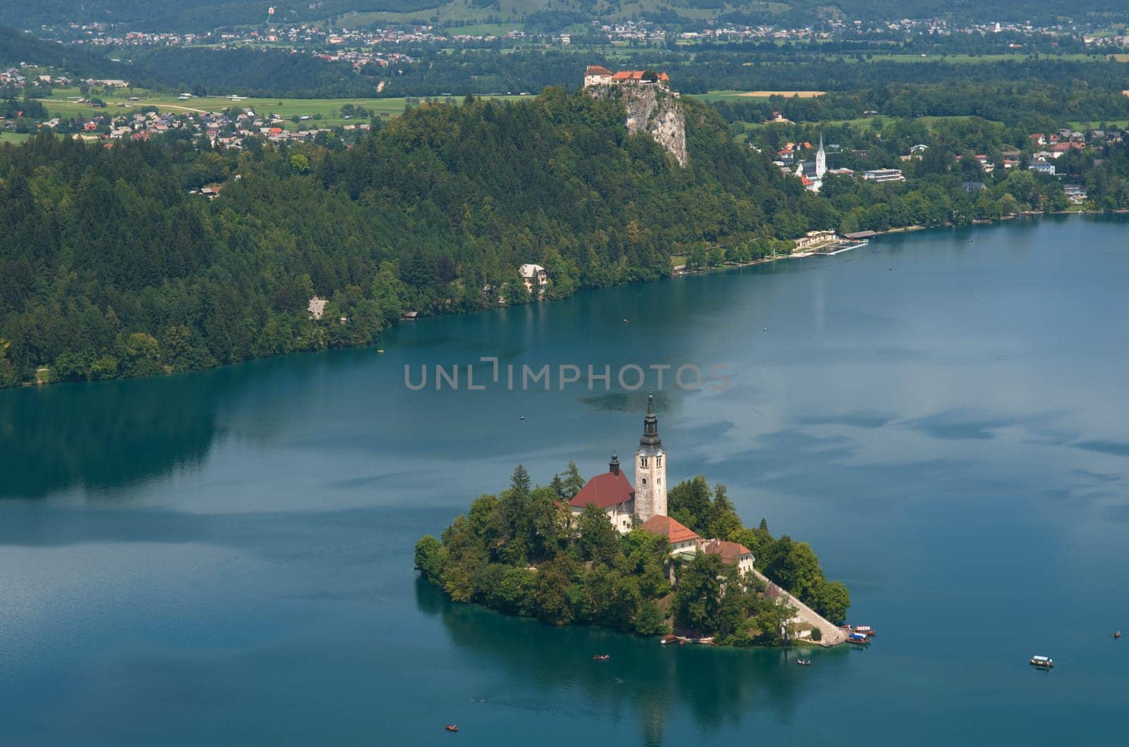 Lake Bled with Island and Castle in Summer. Small boats can be seen on the lake.