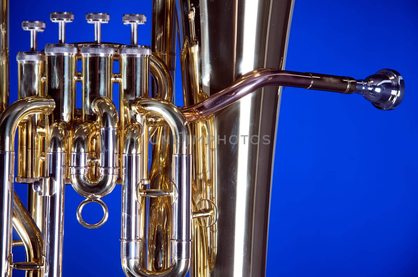 A gold brass bass tuba euphonium isolated on a blue background in the horizontal format with  copy space.