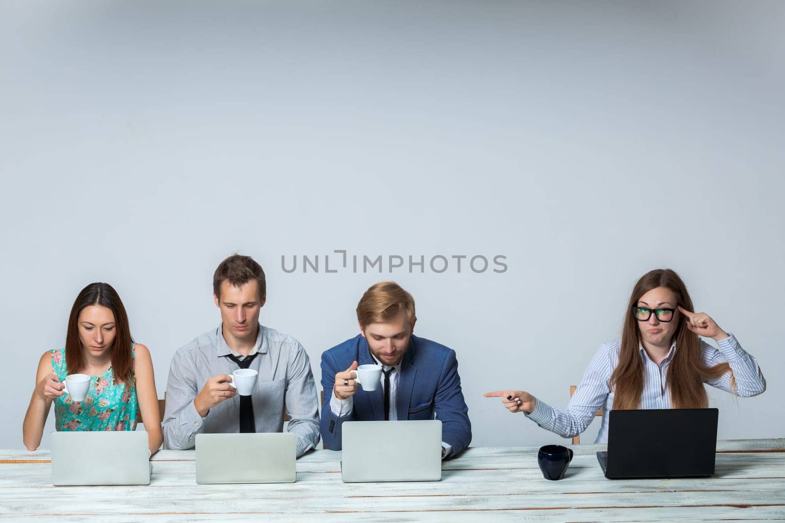 Business team working together at office on light gray background. boss is dissatisfied with the others drinking tea. copyspace image