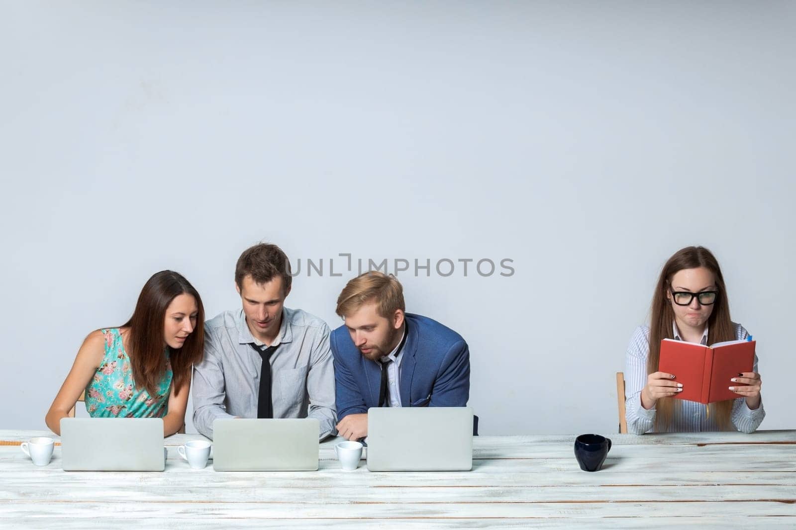 Business team working together at office on light gray background. all working on laptops. boss reading notebook. copyspace image