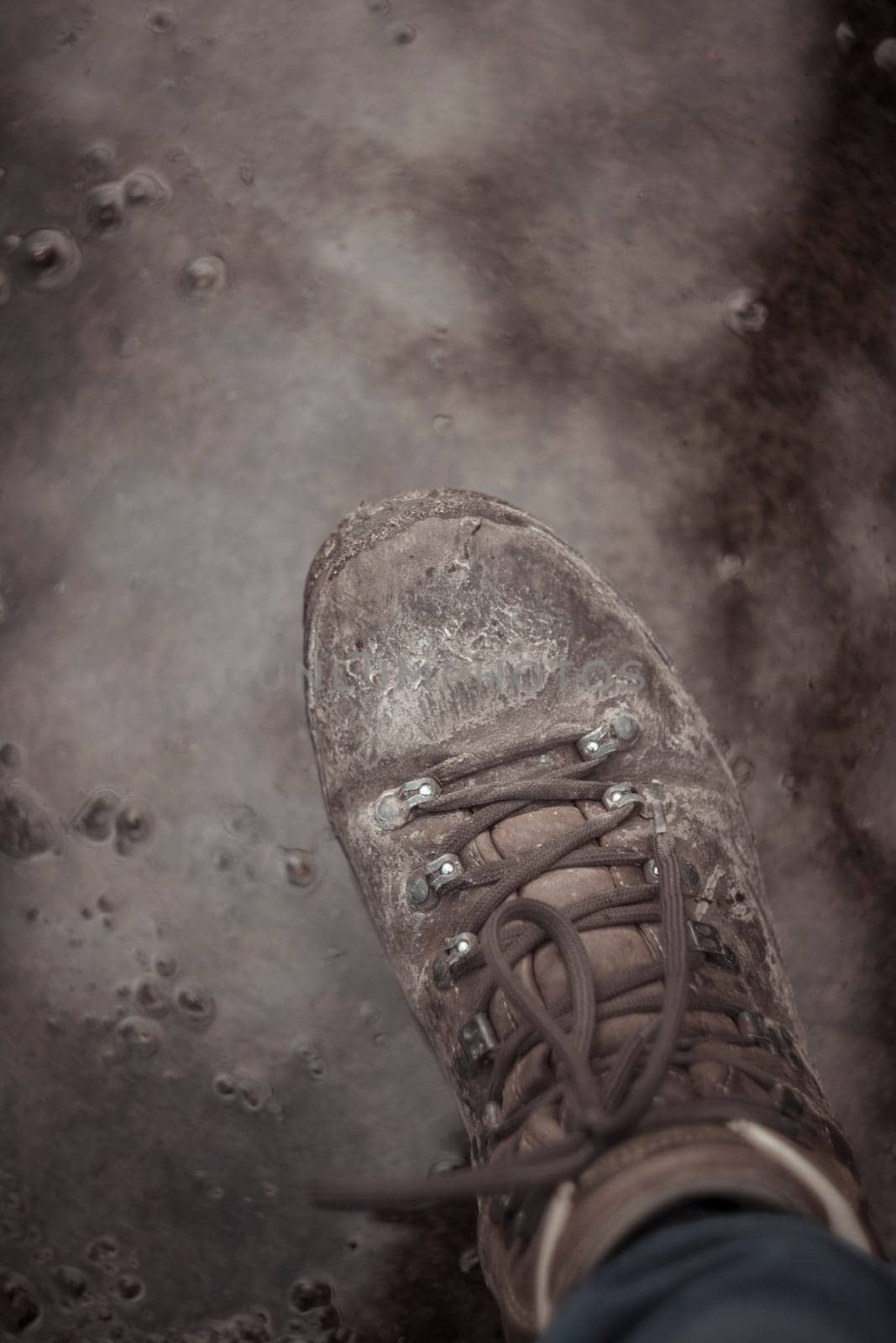 Vertical shot of hiking boot stepping into mud