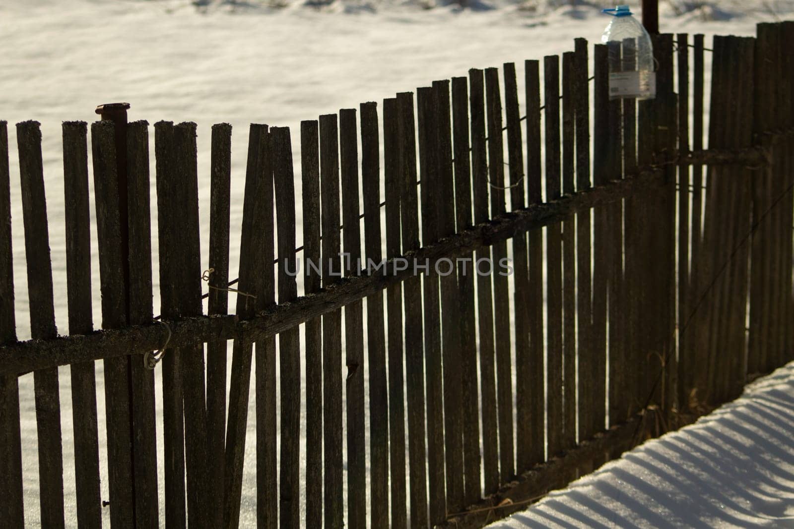 Fence made of wood in winter. Wooden fence in countryside. Territory of farm is in snow.