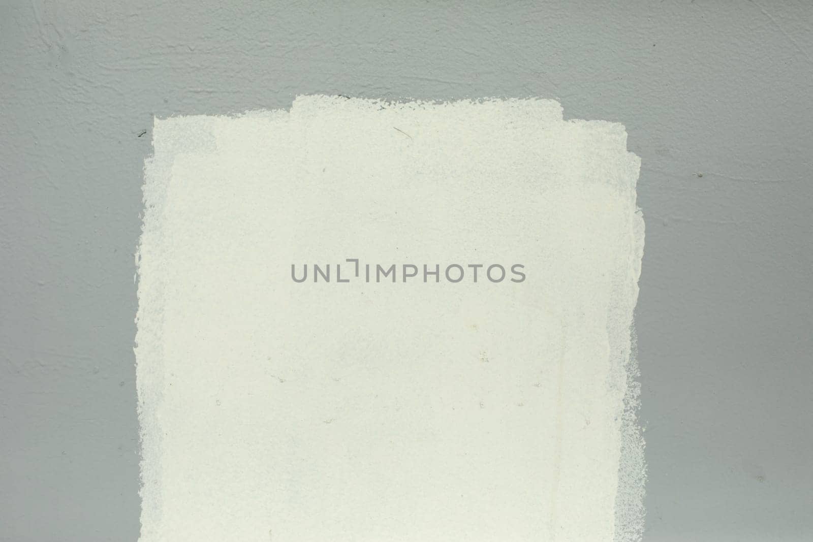 White paint on grey wall. Paint spot white. Smeared inscription. Poor wall painting.