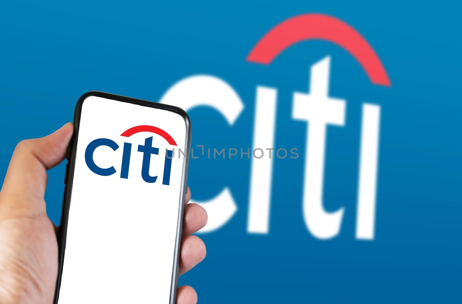 New York, US, March 2023: Hand holding a phone with Citi logo on the screen. Citi logo blurred on blue background. Citi is an American multinational investment bank. Illustrative editorial.