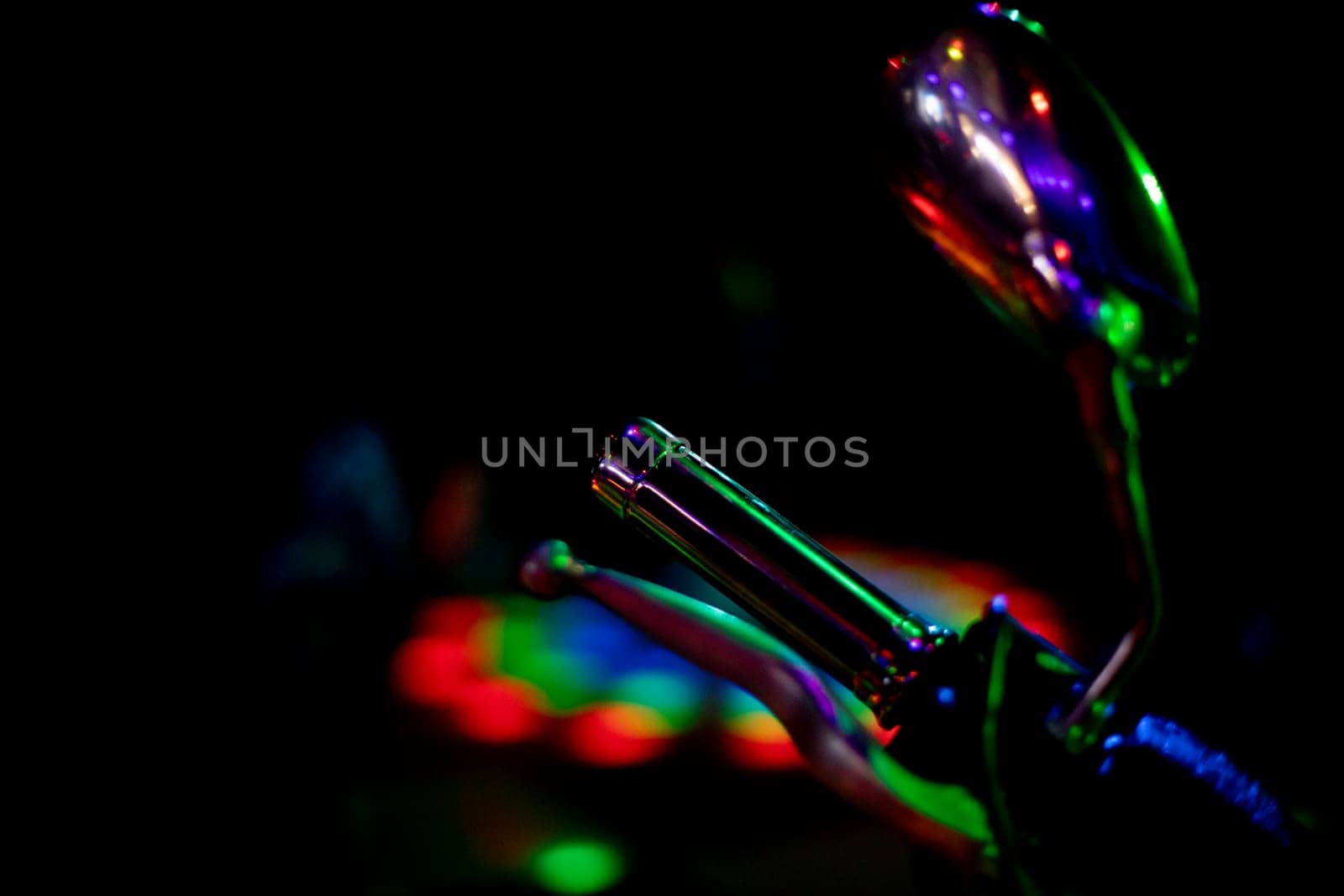 Motorcycle details in colored light. Transport at disco. Light on object. Rearview mirror and motorcycle handle.
