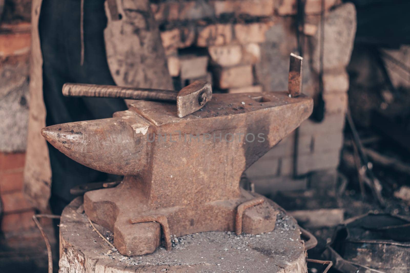 Process metal with hammer on anvil in forge. Strike iron outdoors in workshop with fire. Metalworking, blacksmithing, manufacturing equipment and tools. Traditional technic of making hardware.