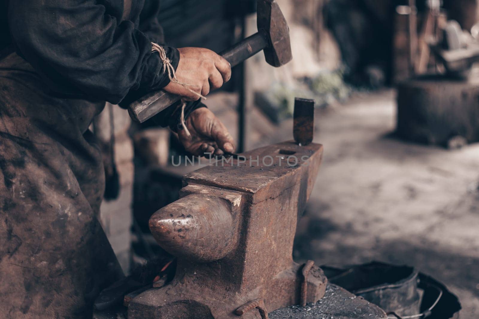 Blacksmith process metal with hammer on anvil in forge. Farrier in dirty clothes strike iron in workshop. Metalworking, manufacturing equipment and tools. Traditional technic of making hardware.