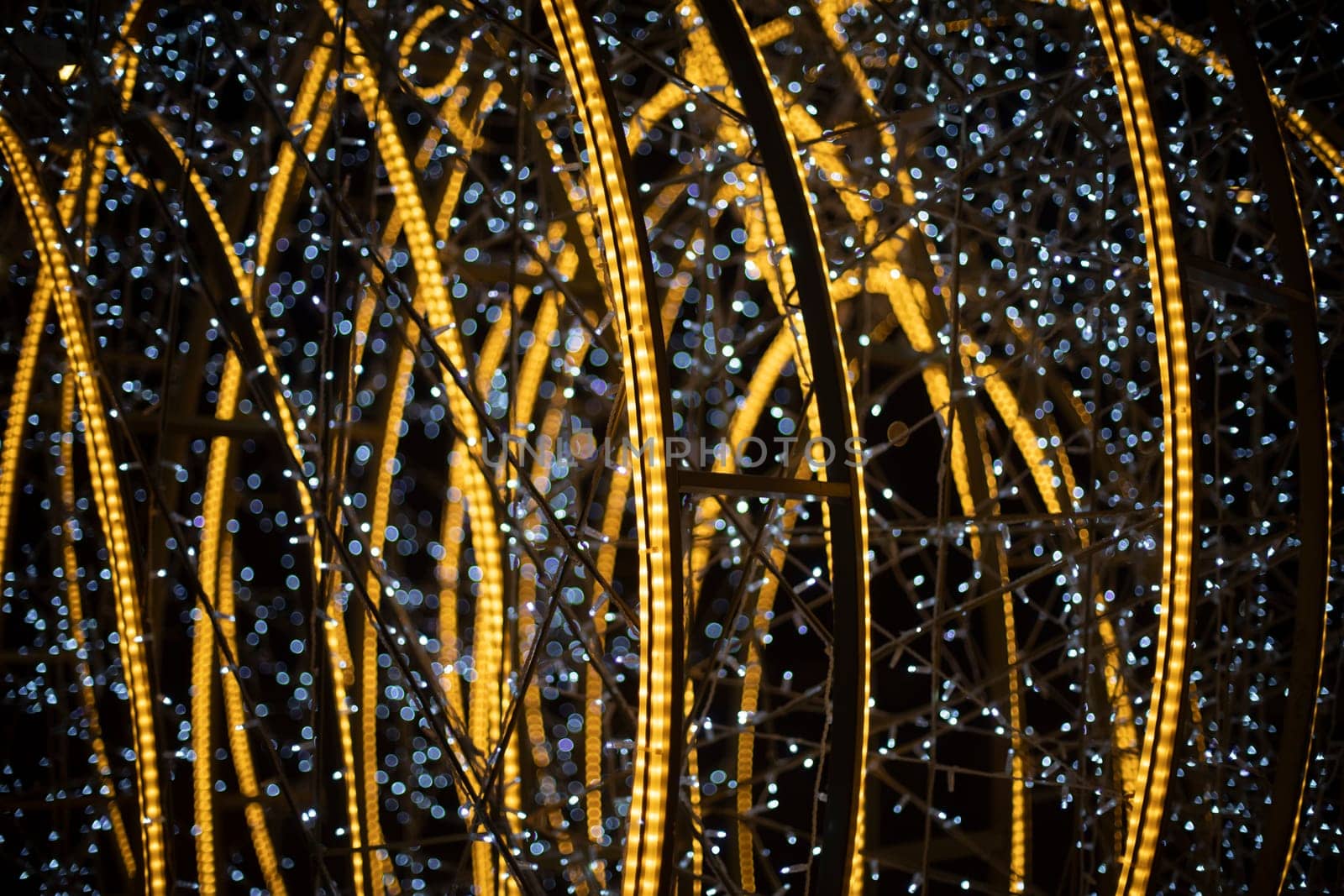 Luminous construction at night in city. Garlands in dark. Decoration of city for holiday. White and yellow LEDs.