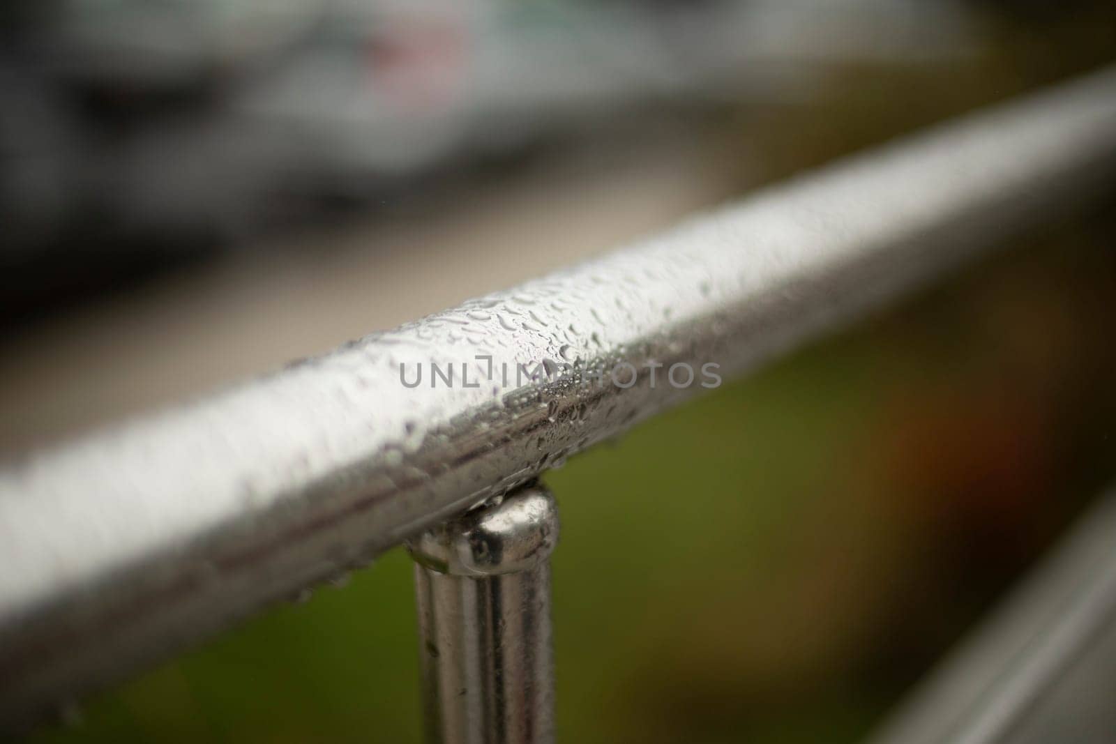 Wet handrail. Steel pipe in water droplets. Silver steel pole. Handrail.