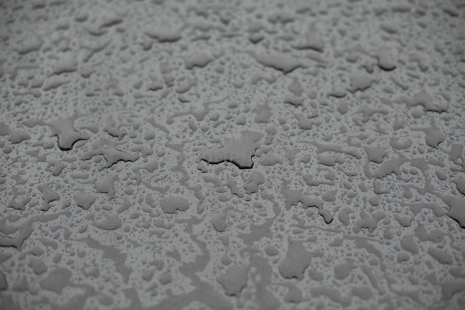 Raindrops on surface. Details of rain. Wet glass. Shades of gray in frame.