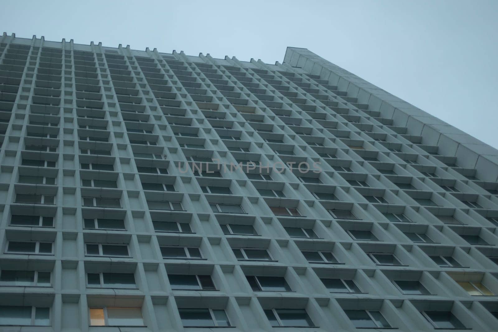 Lots of windows in skyscraper. High-rise building in city. Offices on grey day. Modern architecture of 20th century.