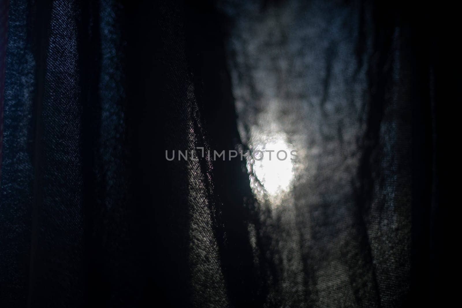 Light through fabric. Curtain on window. Black fabric texture on lumen. Fine mesh.