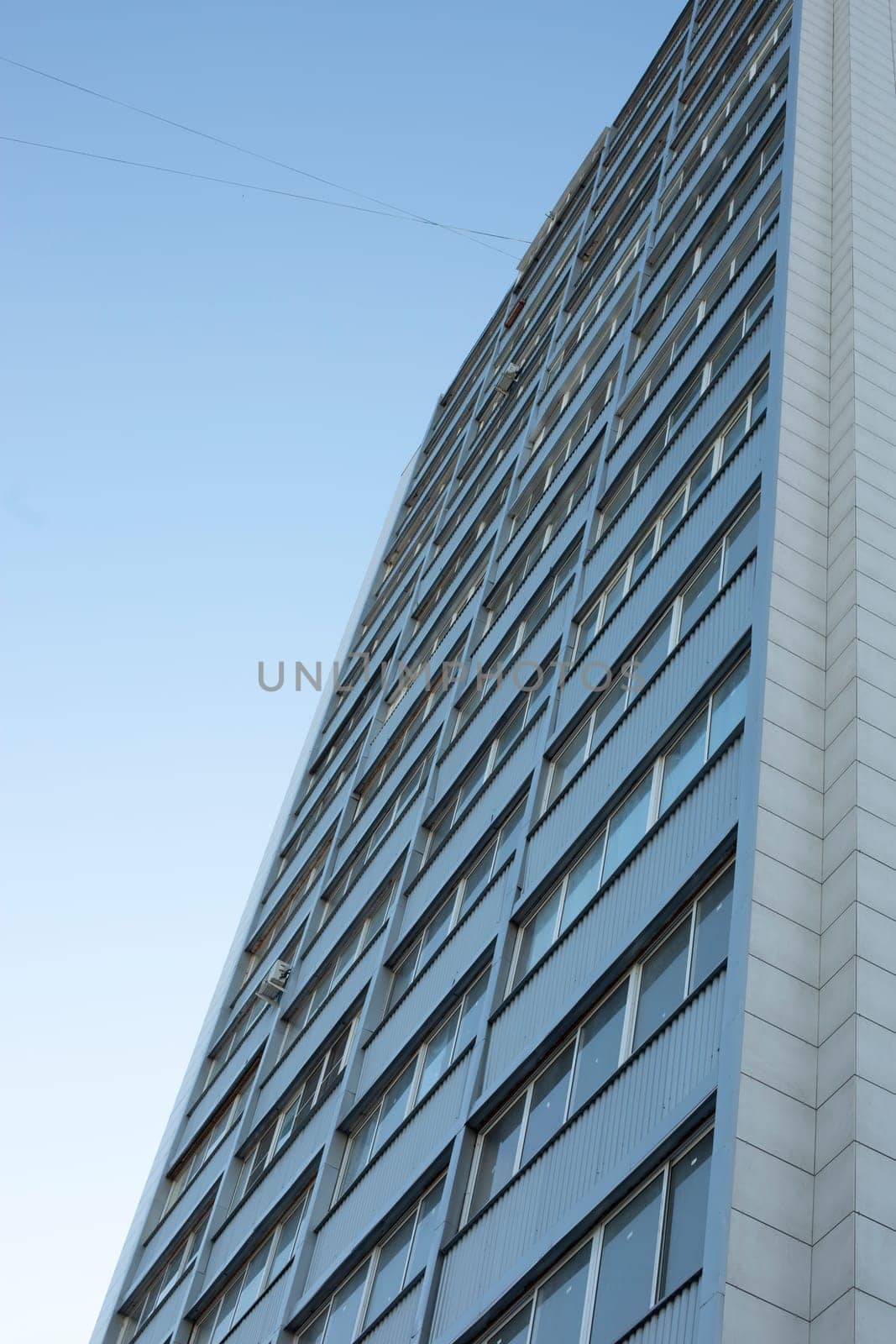 Grey building in city. High house. Windows in residential building. Modern architecture.