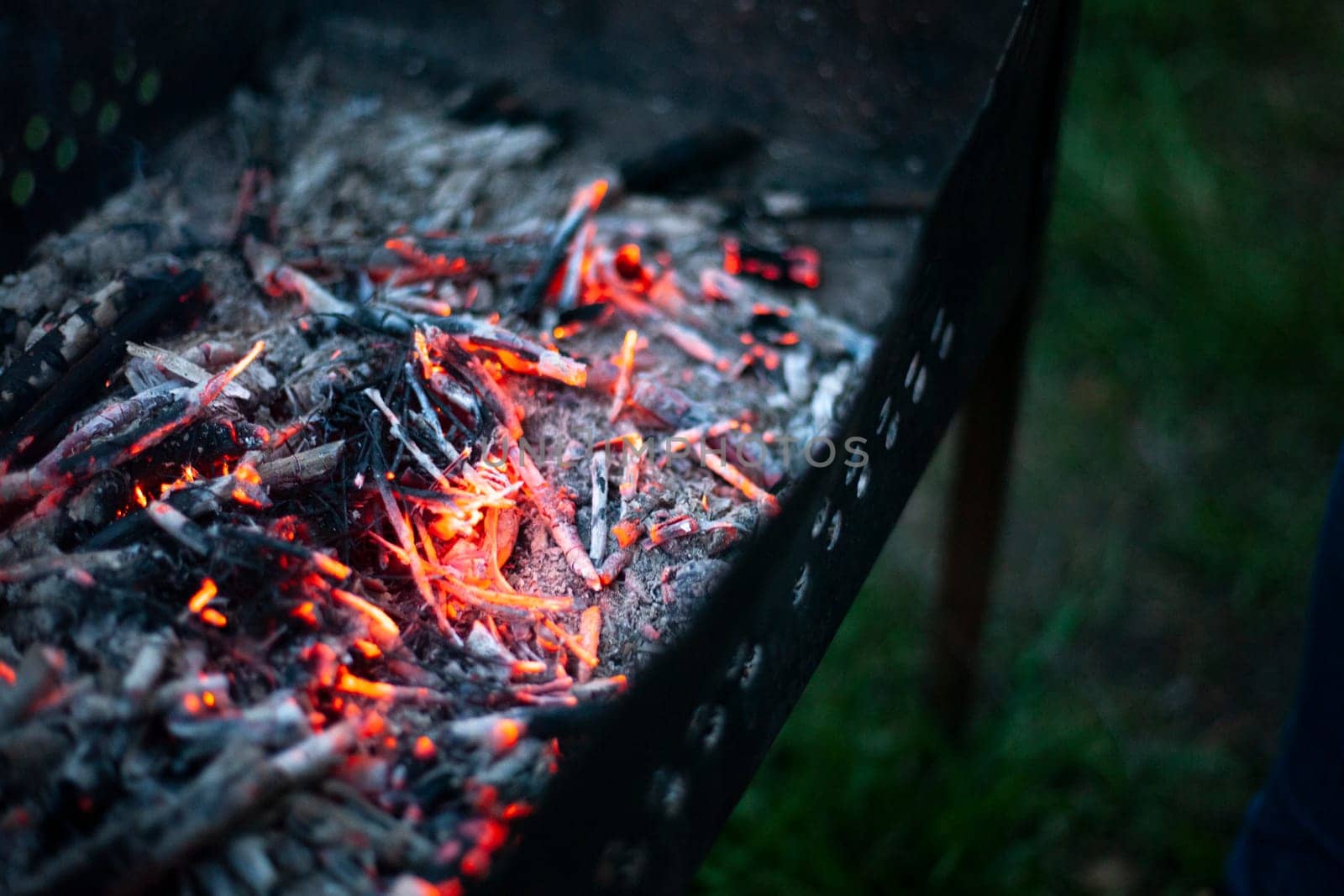 Coals in brazier. Heat from firewood. Burning wood. Grill for cooking. Picnic details.