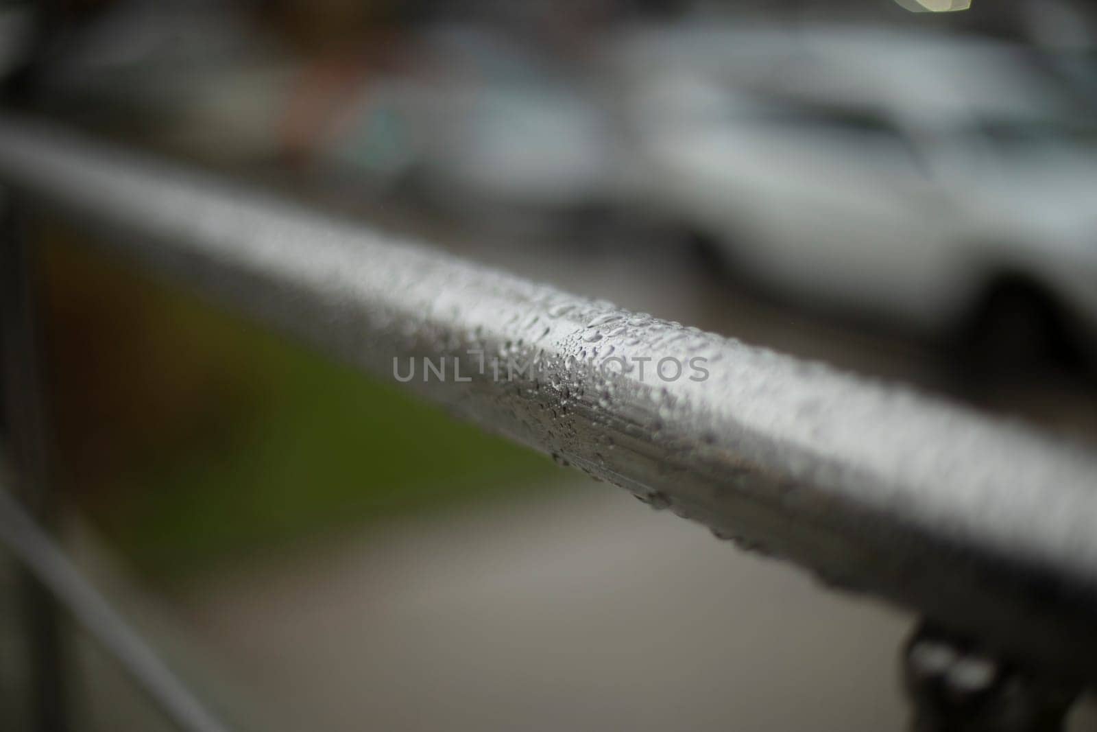 Wet handrail. Steel pipe in water droplets. Silver steel pole. Handrail.