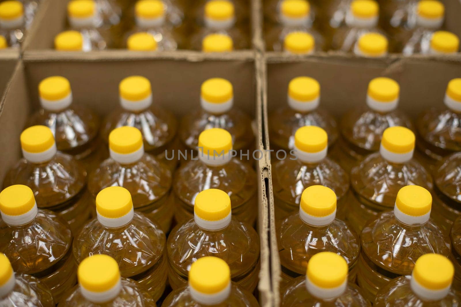 Yellow bottle caps. Sunflower oil in cardboard box. Goods in stock. Bottles stand in row.