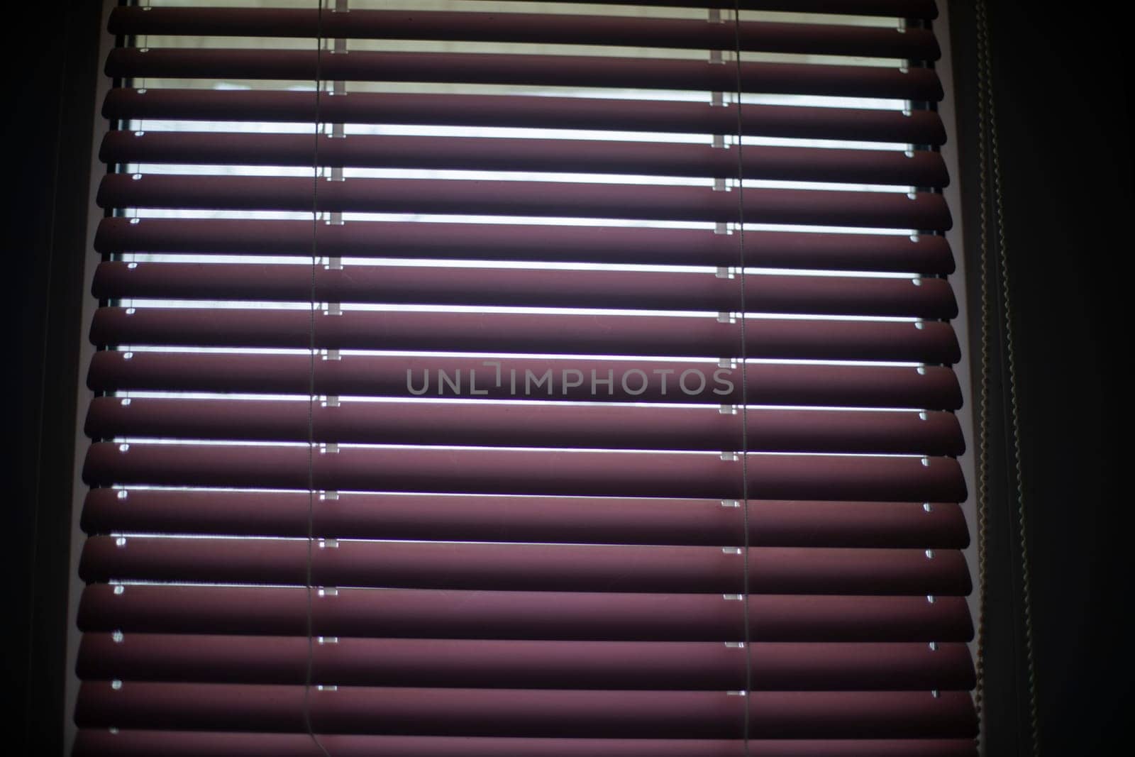 Blinds on window. Window in apartment. Closed blinds. Light through glass.