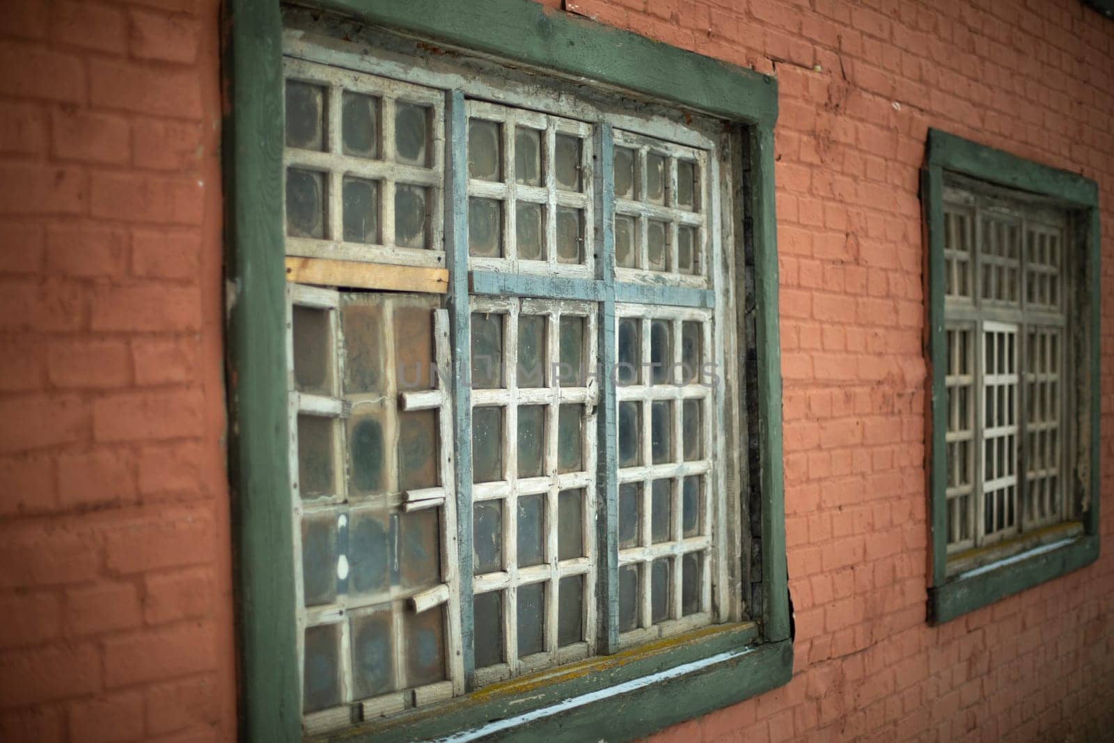 Old window in house. Details of 19th century architecture. Wooden lattice. Window frame. Brick building.