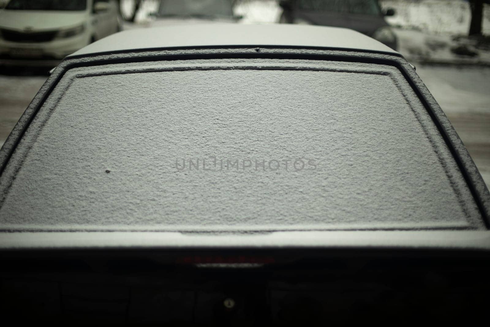 Rear window of car in snow. Snow by car. Car is parked in winter. Snow on glass.