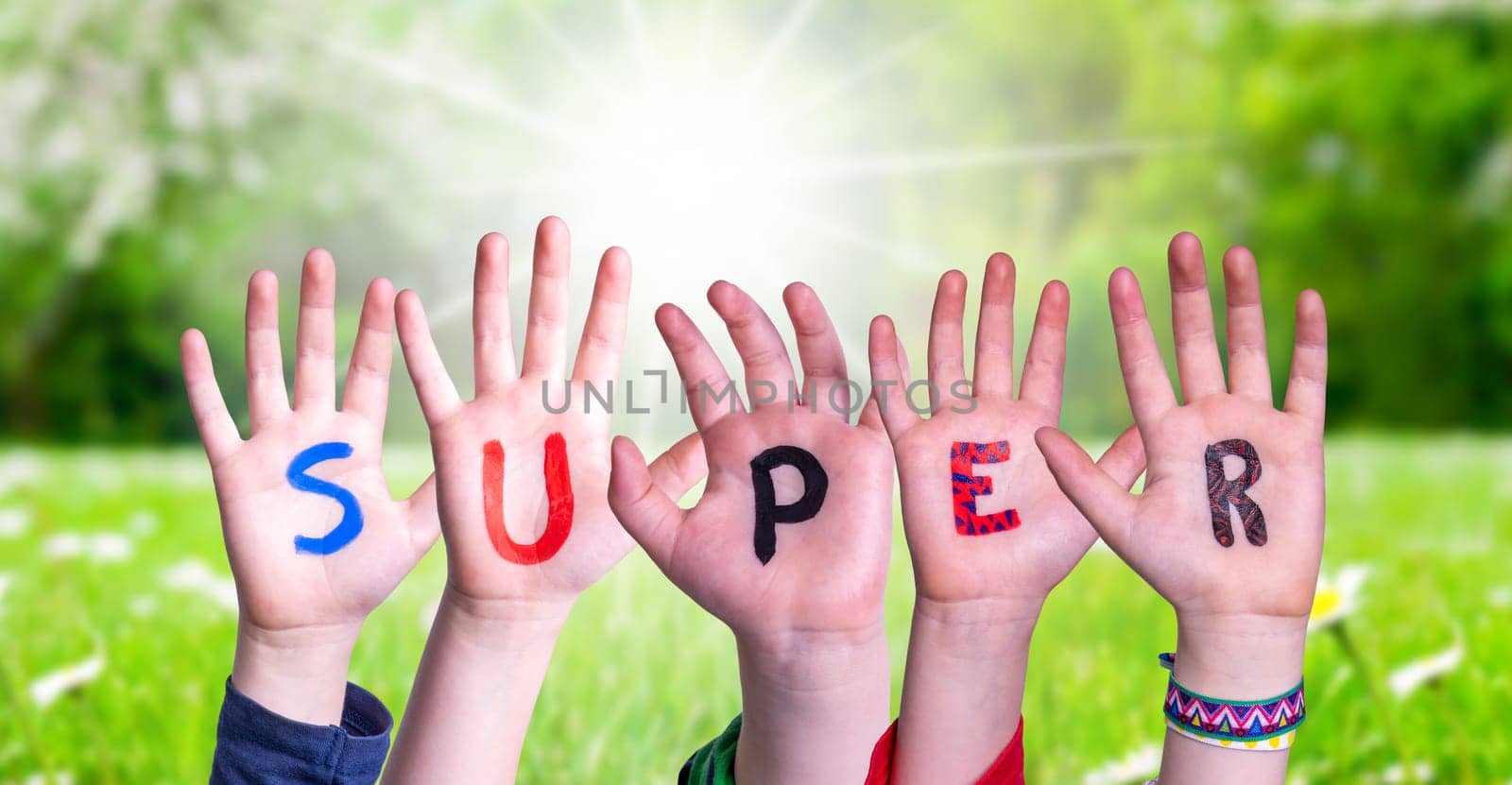 Children Hands Building Colorful English Word Super. Sunny Green Grass Meadow As Background.