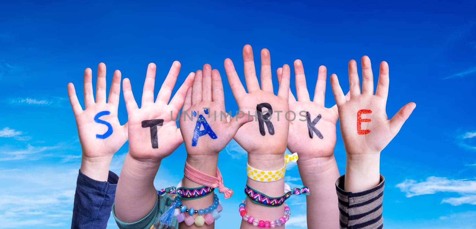 Children Hands Building Colorful German Word Staerke Means Strength. Blue Sky As Background.
