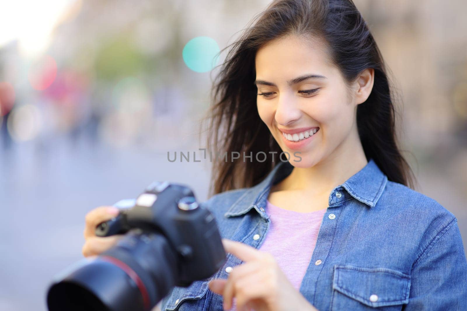 Happy photographer checking photos on camera in the street