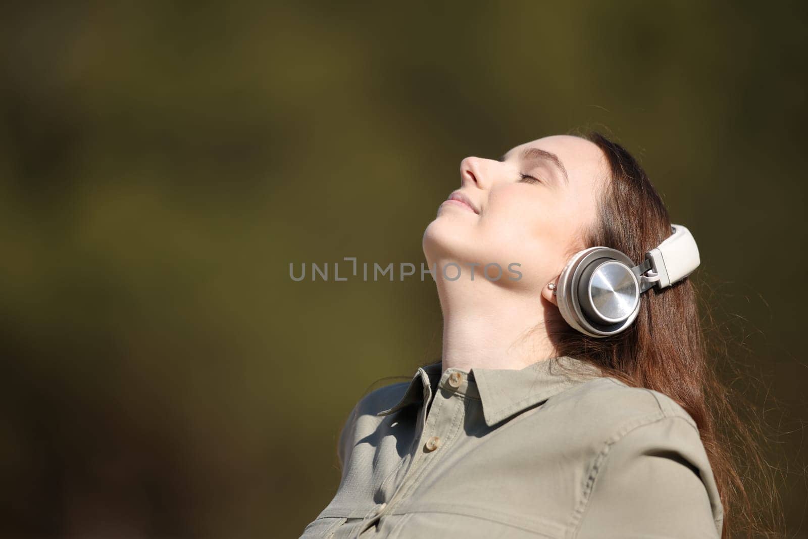Woman meditating outside listening audio guide with headphone