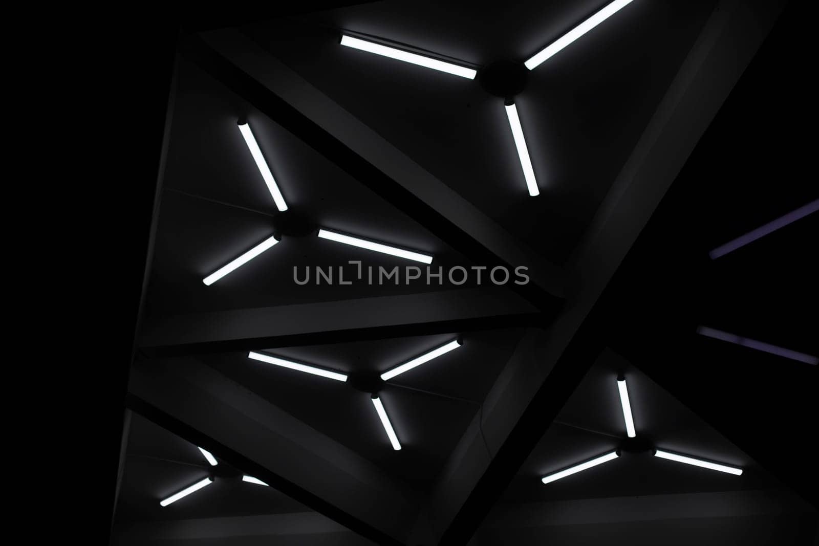Triangular fluorescent lamps. Ceiling design. Interior details. Futuristic light. Low light.