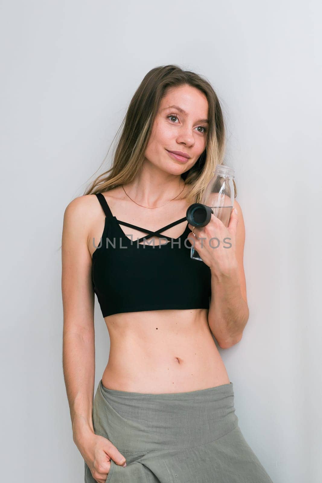 Sporty young woman drinking water after training at home. Active lifestyle and wellness