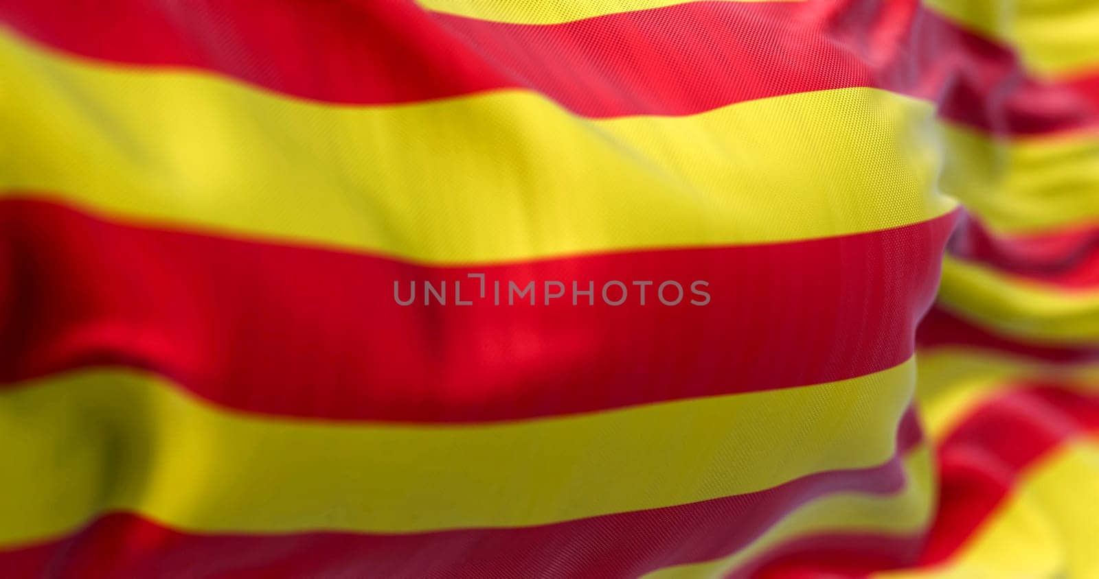 Detail of the Catalonia flag waving in the wind. Catalonia is an autonomous community of Spain. Four red stripes on a yellow field. 3d illustration render. Selective focus. Close-up