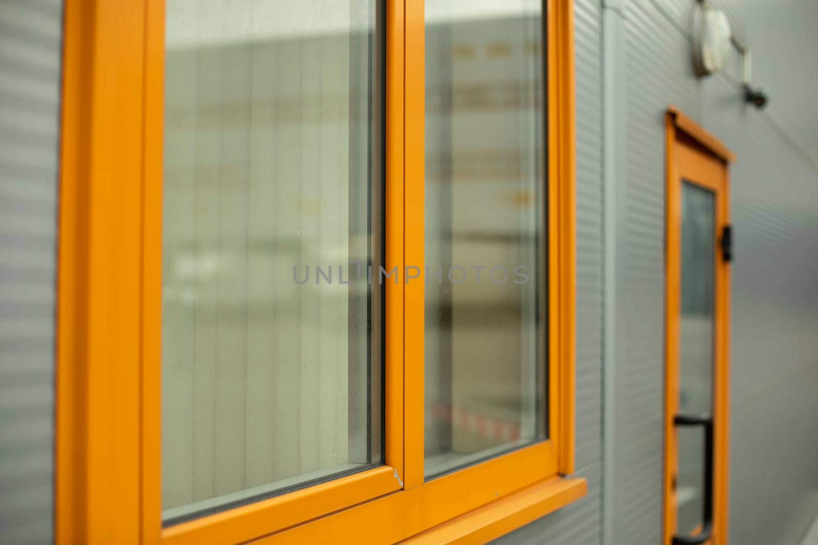 Orange window in building. Details of house. Industrial building. Wall surface with window.