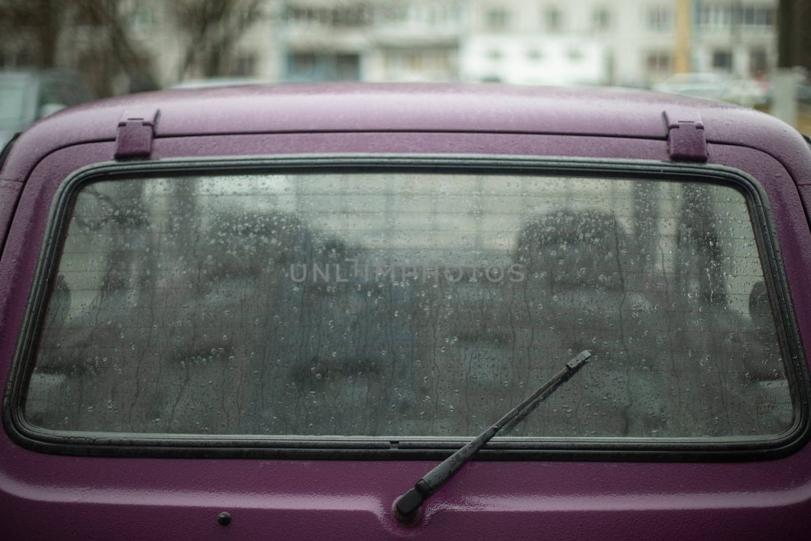 Car window is lighter in rain. Wet car in parking lot. Details of old transport. Wiper.