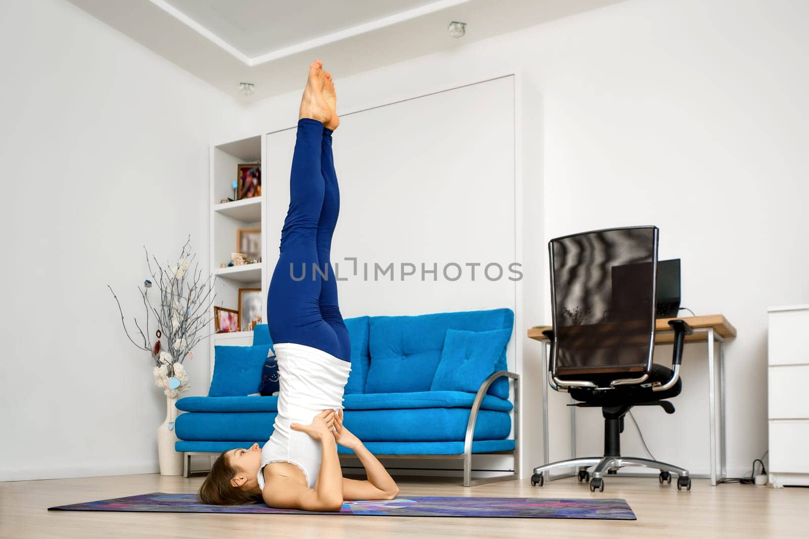 Young woman does supported shoulderstand yoga pose