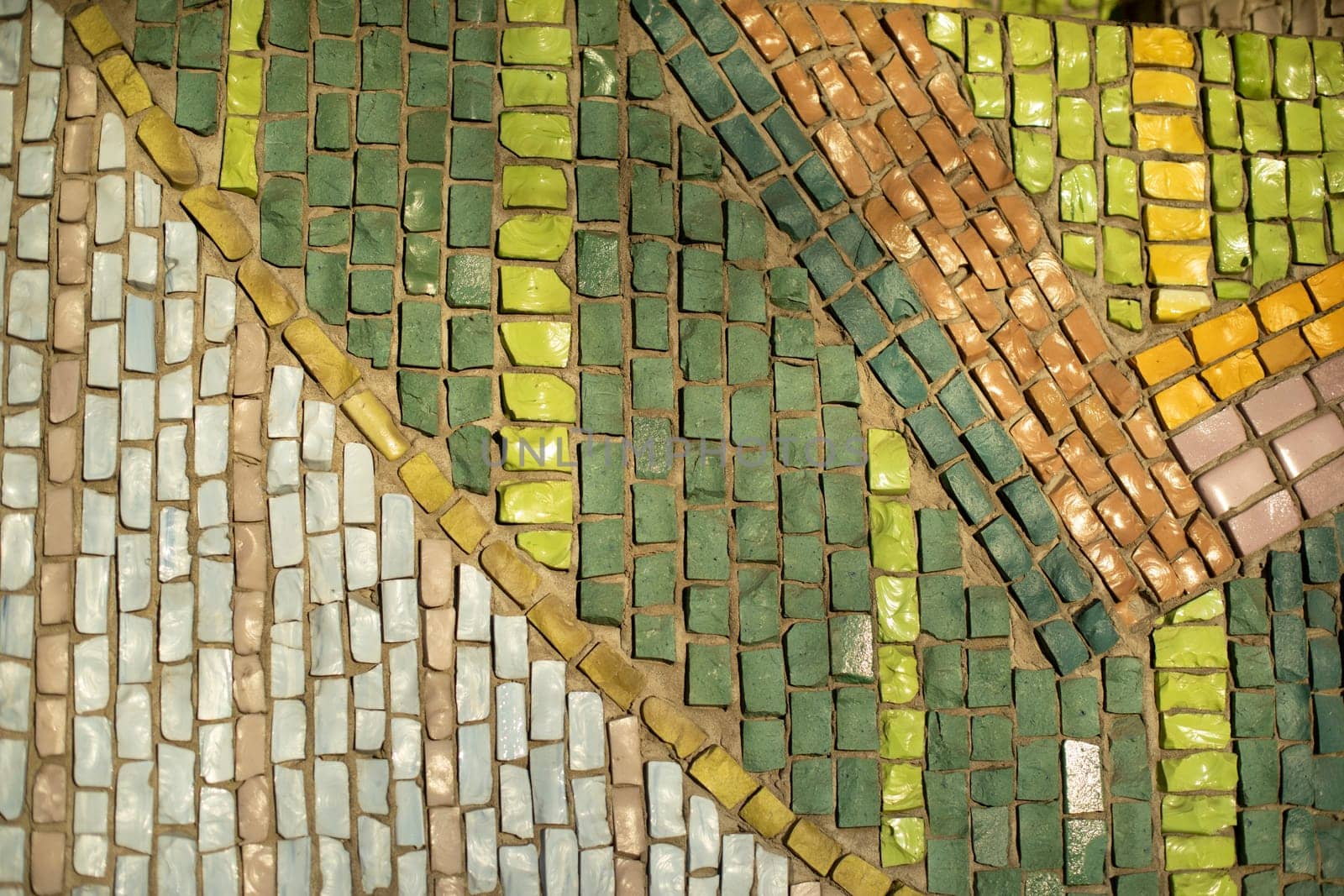 Tile texture. Mosaic of colored stone. Green pieces of stone lined up in row. Details of building.